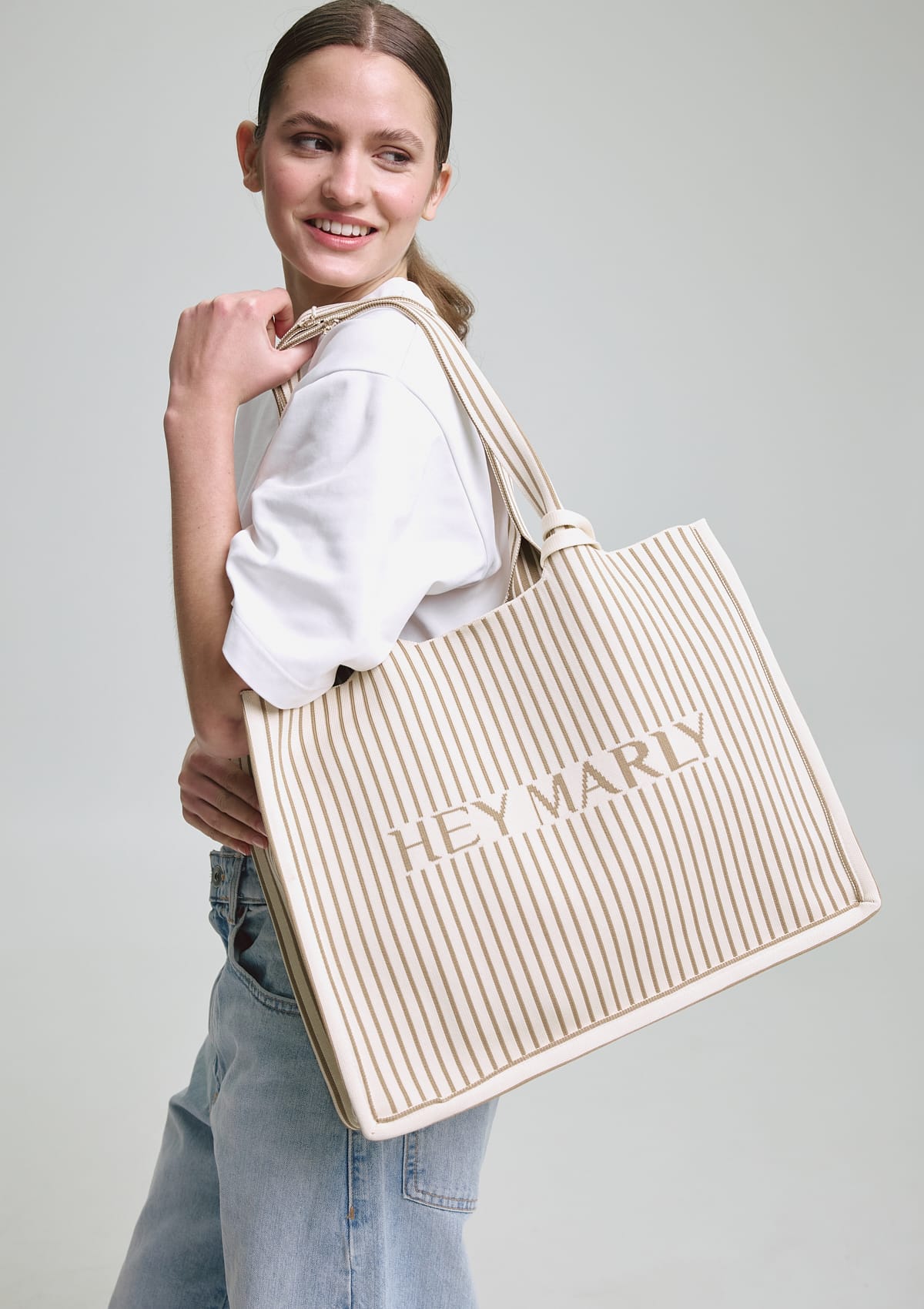 Tragebild mit Model auf neutralem Hintergrund des Produktes Casual Signature Bag in der Farbe Crema-Sand