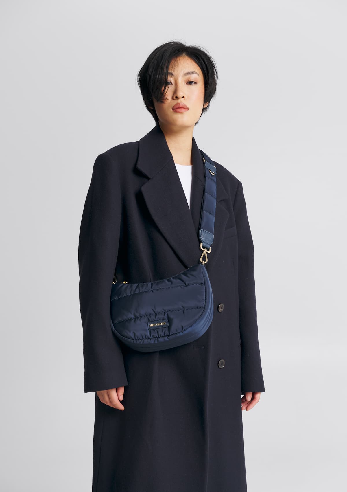 Tragebild mit Model auf neutralem Hintergrund des Produktes Puffy Nylon Strap in der Farbe Deep Blue