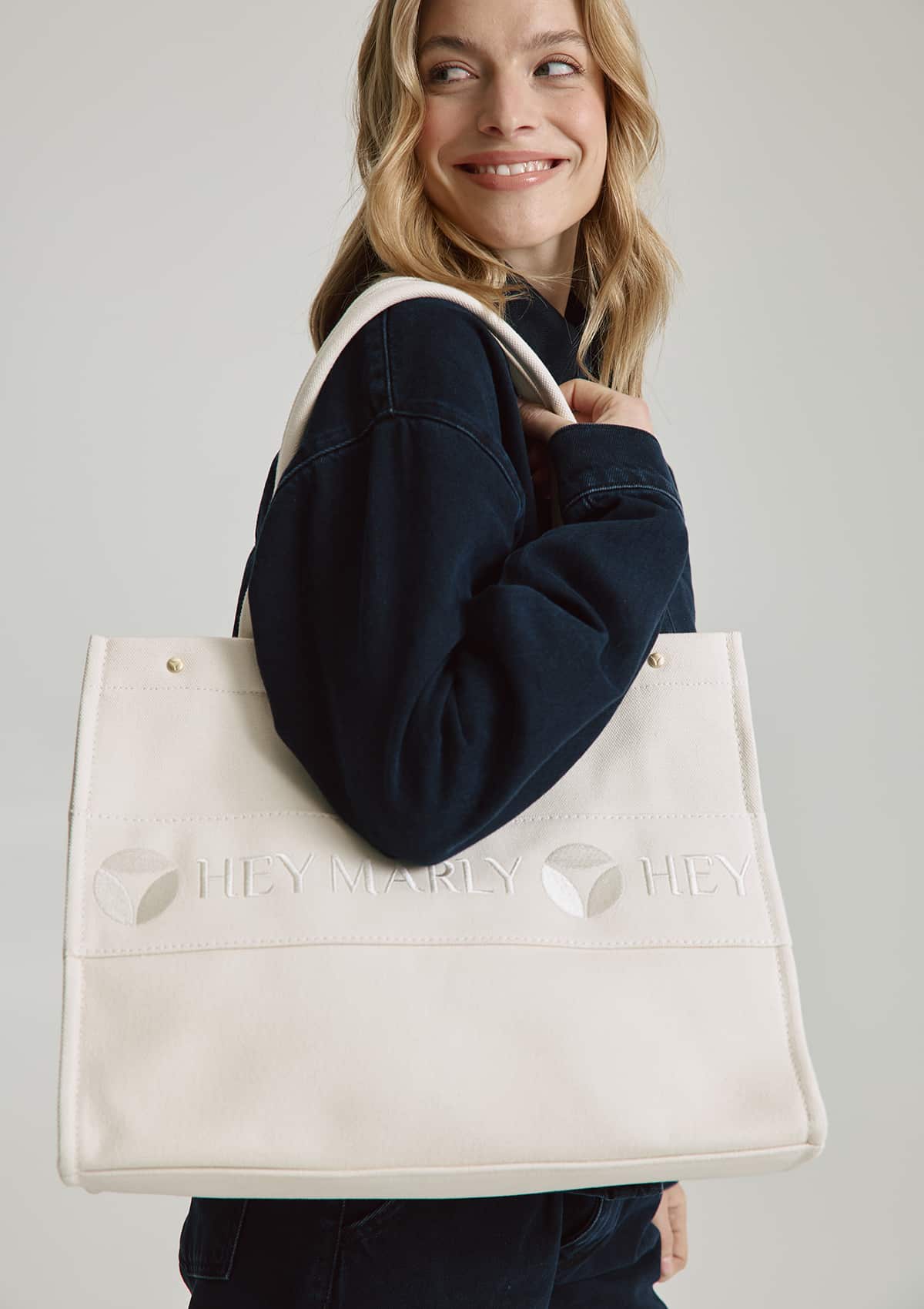 Tragebild mit Model auf neutralem Hintergrund des Produktes Signature Bag in der Farbe Crema