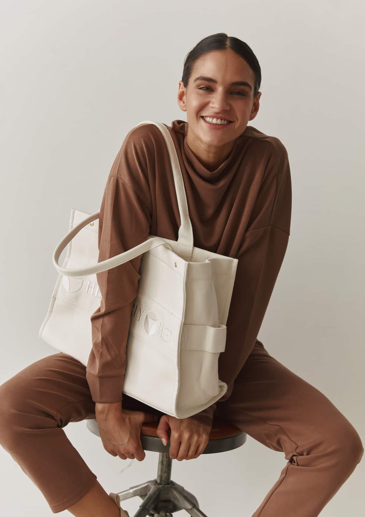 Tragebild mit Model auf neutralem Hintergrund des Produktes Signature Bag in der Farbe Crema
