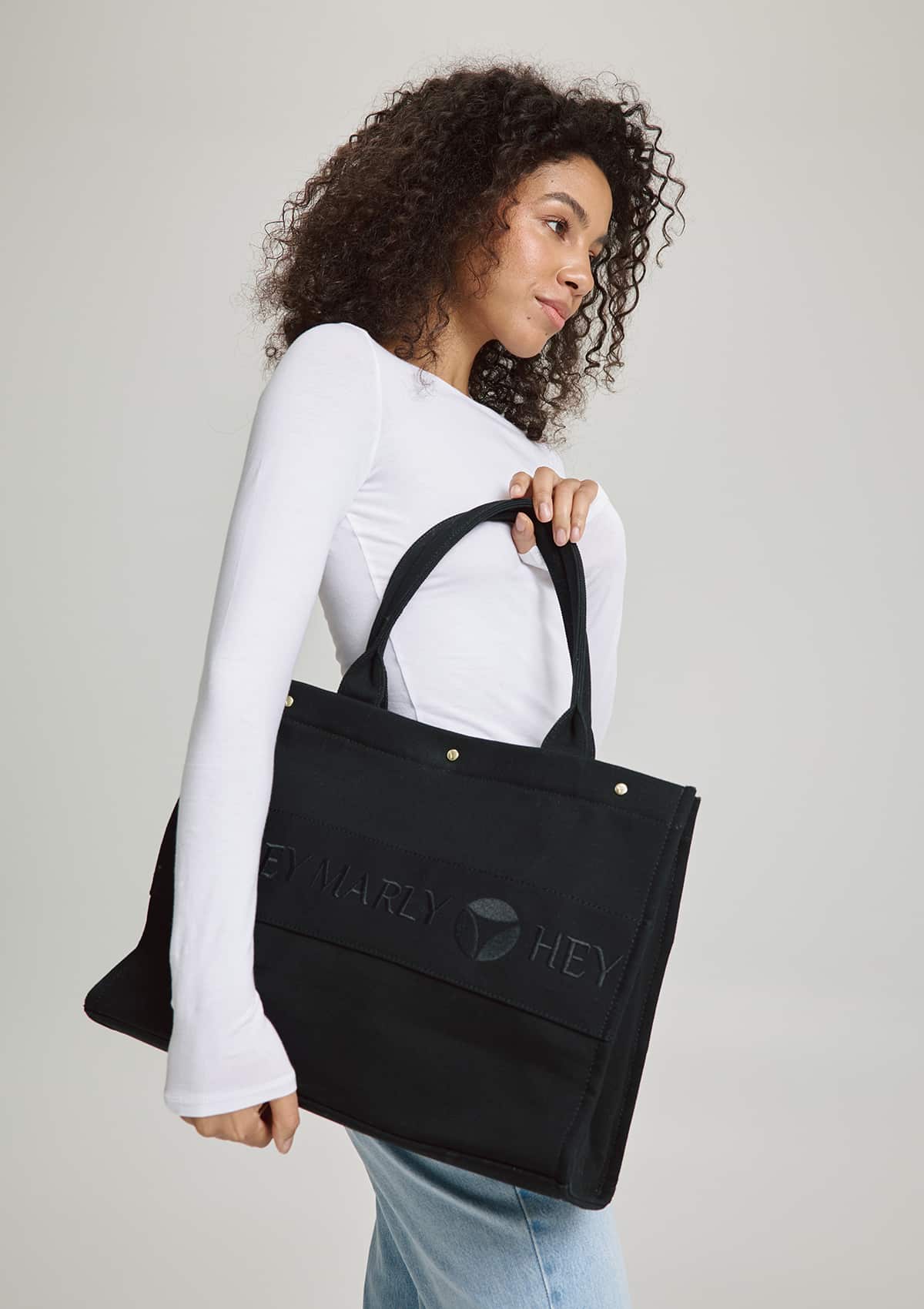Tragebild mit Model auf neutralem Hintergrund des Produktes Signature Bag in der Farbe Black
