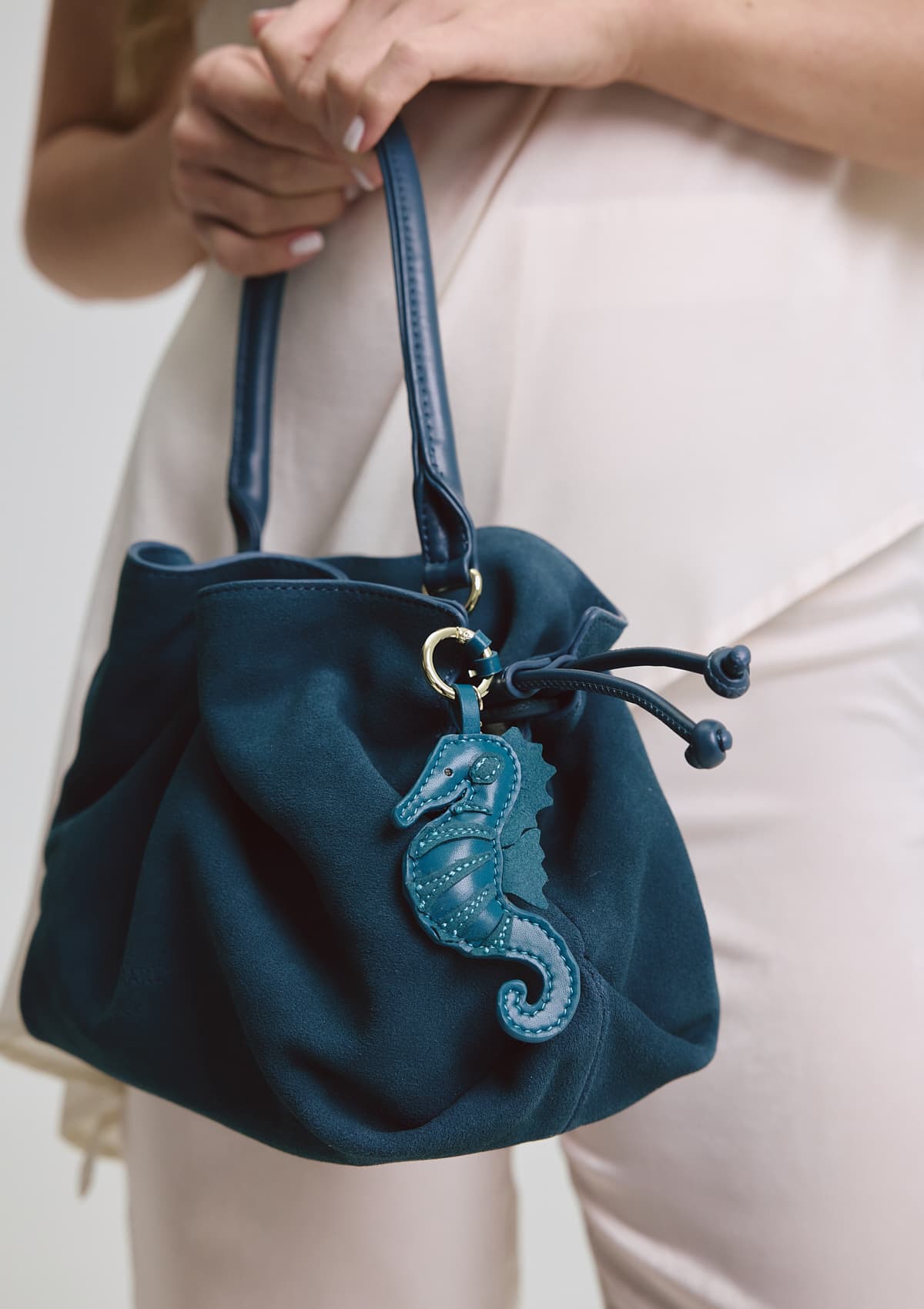 Tragebild mit Model auf neutralem Hintergrund des Produktes Seahorse Charm in der Farbe Teal